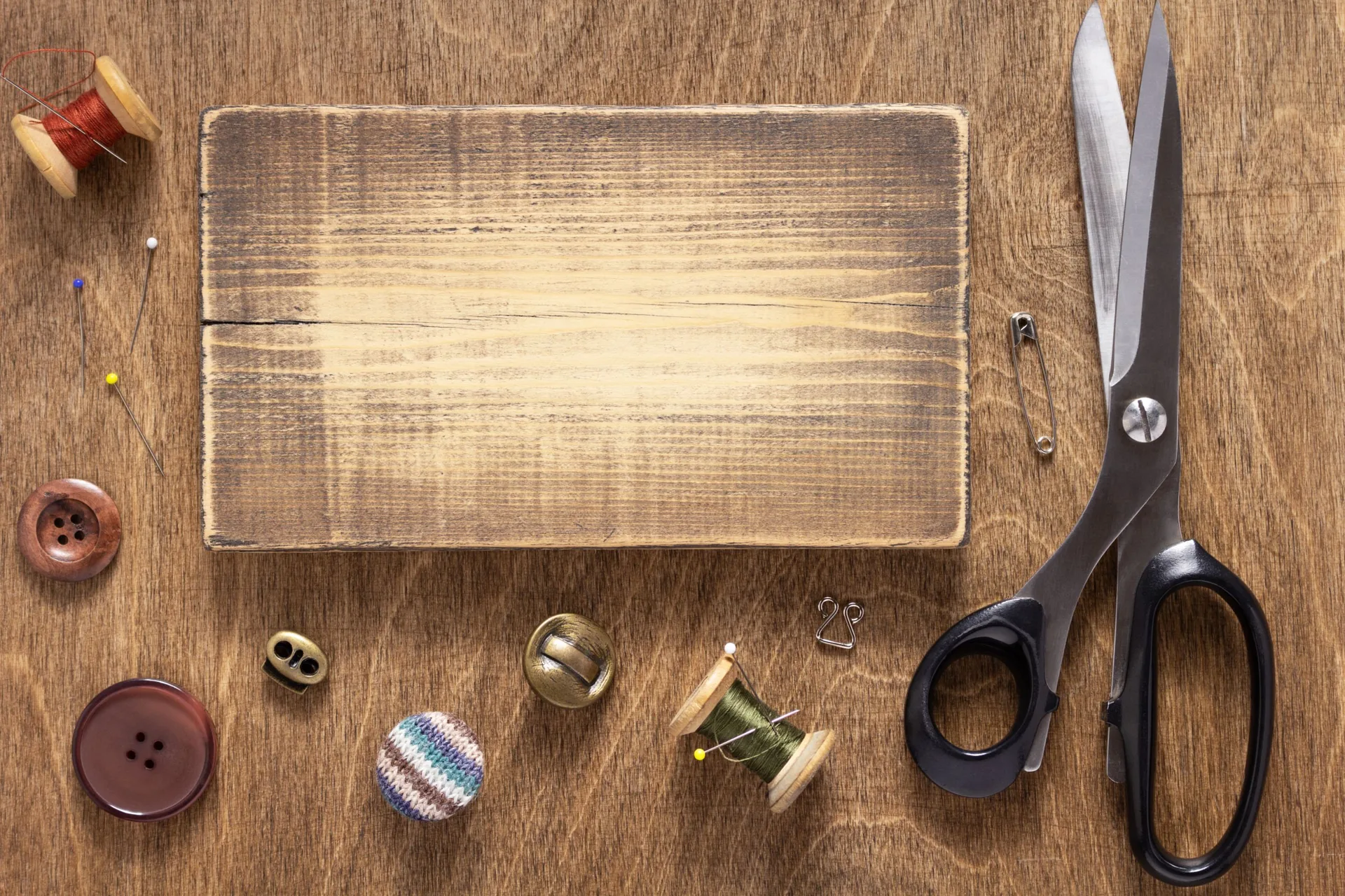 Tailoring shears, thread spools and measuring tape on a workbench